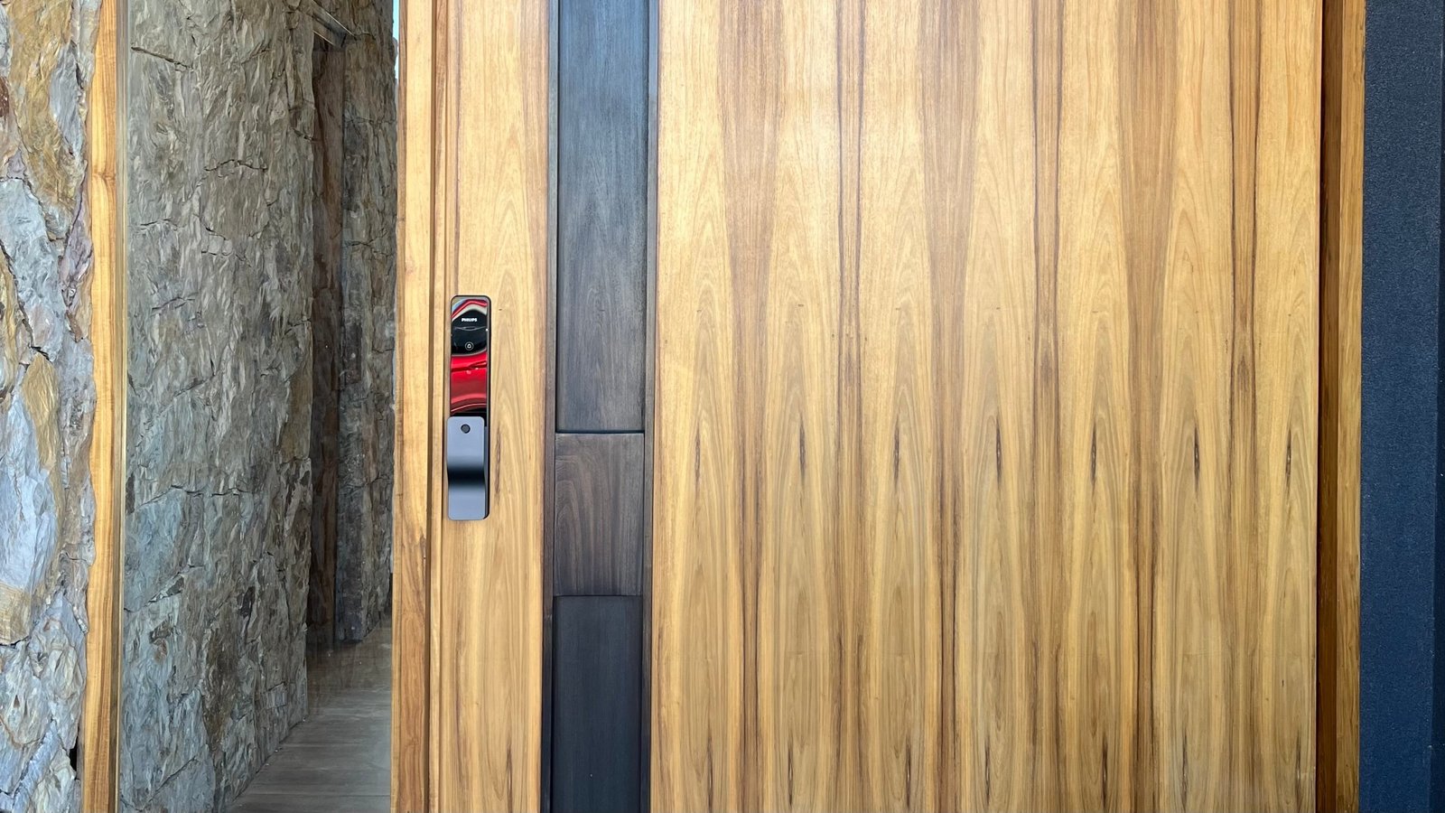 Cerradura Philips instalada en una puerta de madera con listón oscuro y pared de piedra, Mendoza